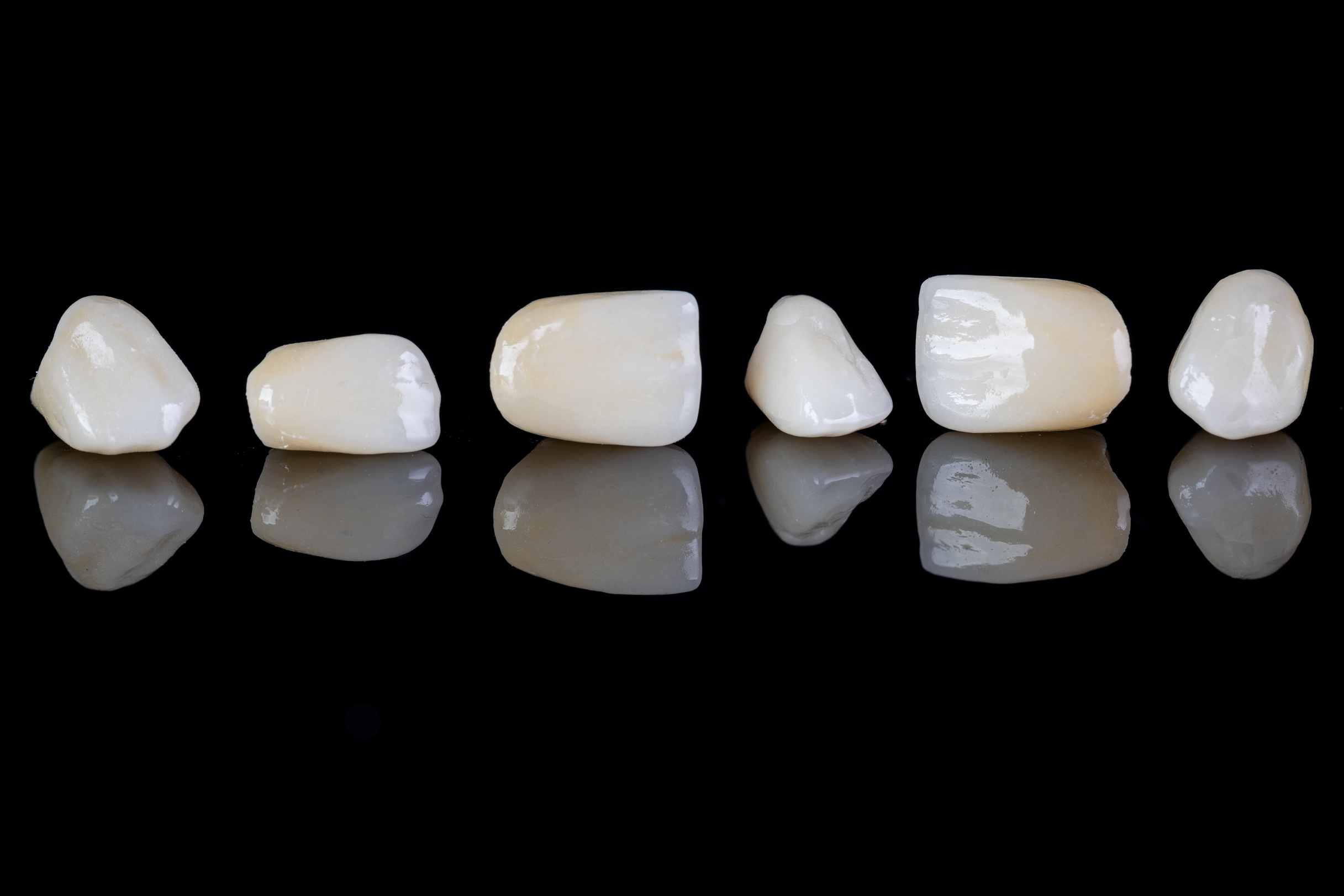 Ceramic dentures and crowns on black background. Dental health care. Ceramic zirconium in final version.